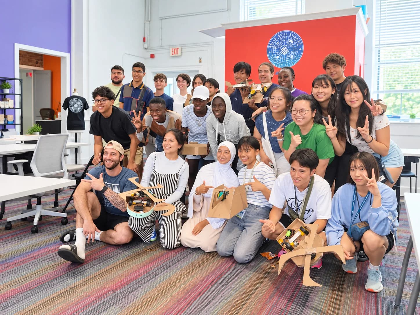A group gathered in the Guild Hall studio holding handmade robot projects