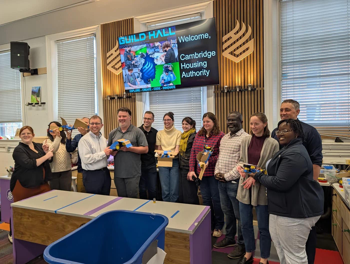 An adult workshop group displaying their completed cardboard robots