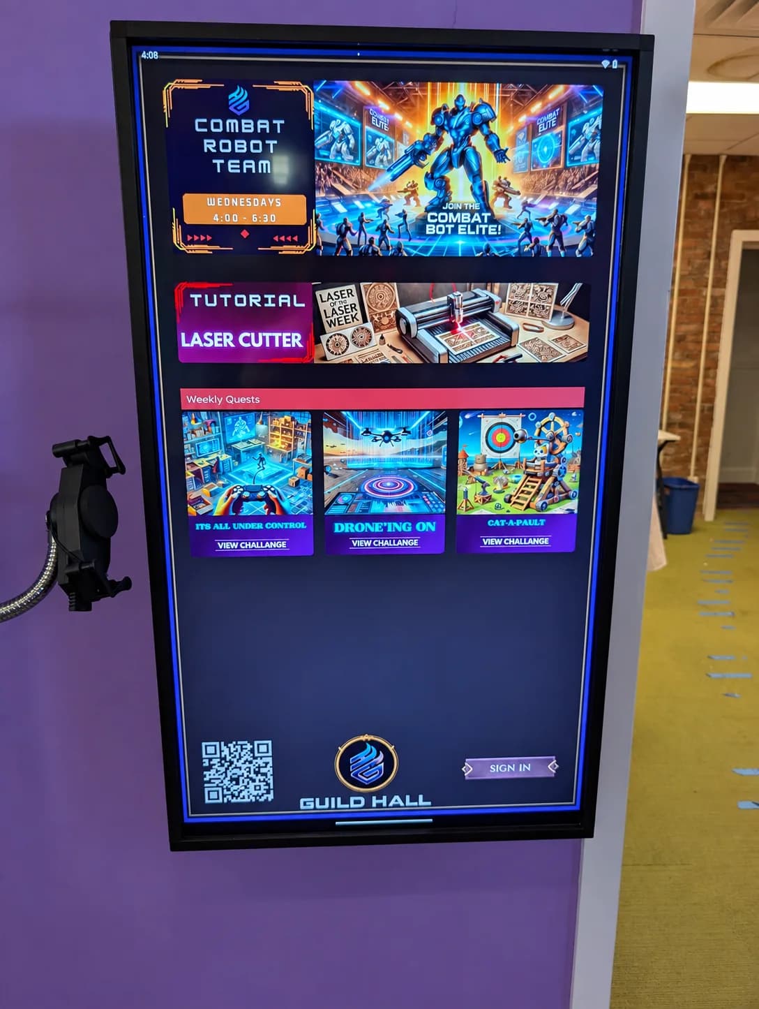 A studio display showing maker challenges, a laser cutter tutorial and a sign-in option