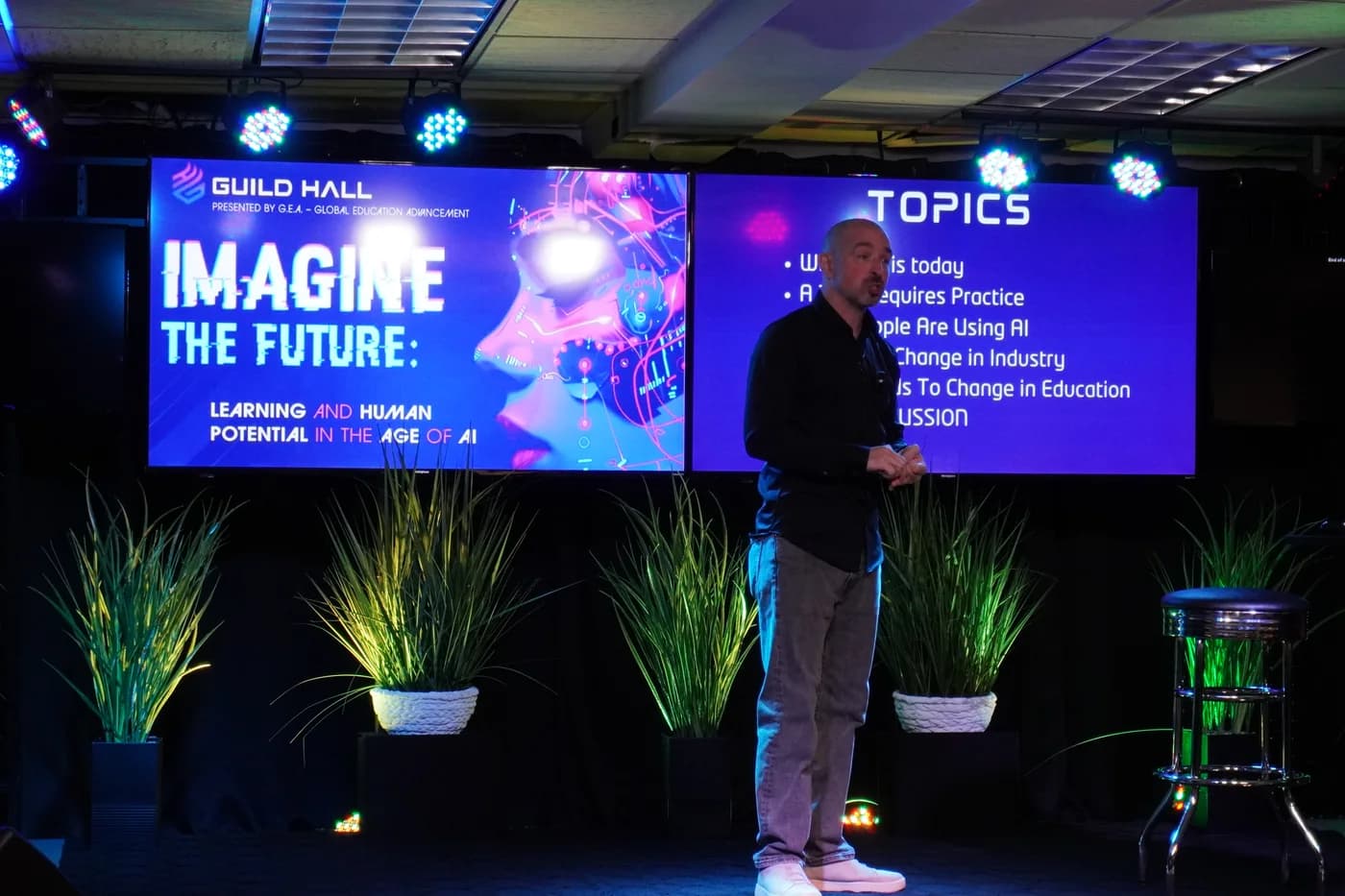 A presenter on stage discussing learning and human potential in the age of AI
