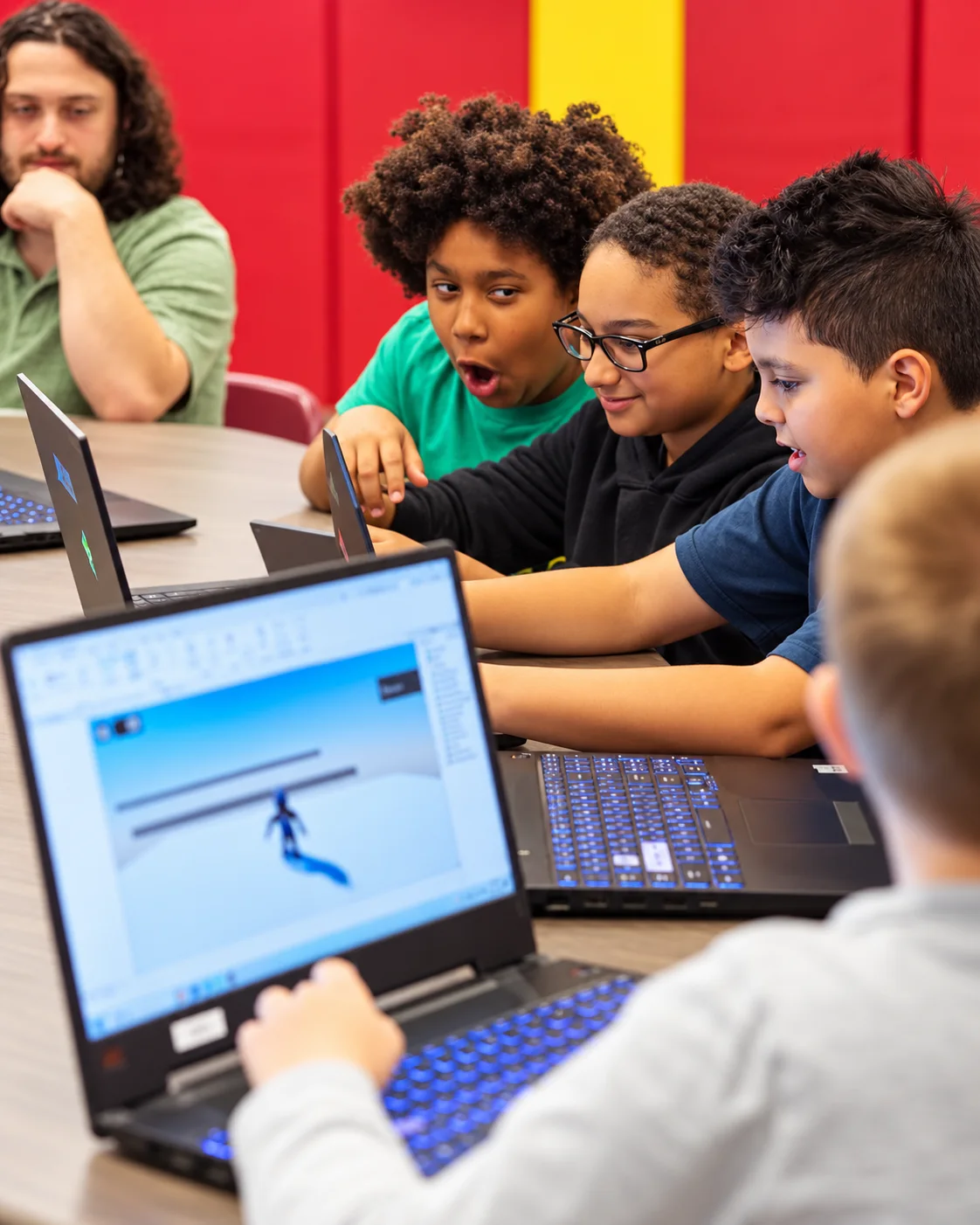 Young learners collaborating on laptops during a game design activity