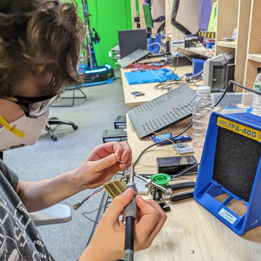 A learner soldering a circuit board at a Guild Hall electronics workbench